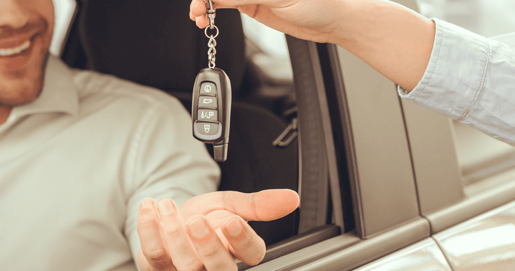 Man sitting in the driver seat of a car and receiving keys for a test drive